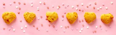 Bir sürü ev yapımı kalp şeklinde kurabiyeler renkli minik konfetiler, serpiştirilmiş yiyecekler. Sevgililer Günü için pembe arka plan afişi, kadınlar günü, aşk, parti deseni.