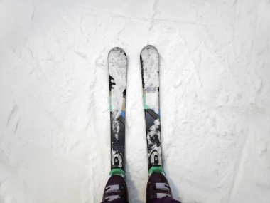 Yukarıda beyaz buz gibi kar yüzeyinde kayak yapan kadın bacakları, dağ geçidi arkaplanı, yokuş aşağı giden kayakçı bacakları düz sıra kayak pistine başlıyor. Kış aktif spor açık hava konsepti.