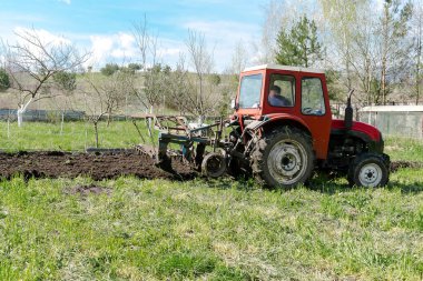 İlkbaharda çiftlikte tarımsal tarla sürme makineleri. Çiftçi bitki ve ekin ekmeden önce toprak ekip biçiyor ve ekiyor, kırsal doğa manzarası..