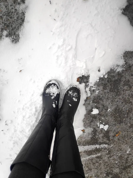 在白色冰雪表面背景的黑色皮靴上 可以看到女性腿上方的近景 冬季走在街头户外的概念 — 图库照片
