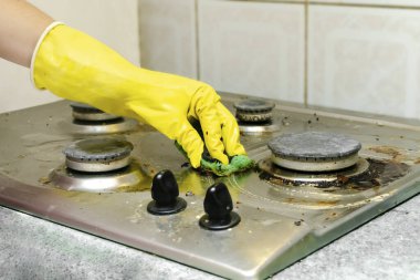 Kirli gaz sobasını yağdan temizlemek, yemek artıkları. Kadın eli koruyucu eldivende sünger bezi ve deterjan ile mutfak sobası yıkıyor. ev temizliği hizmeti kavramı.