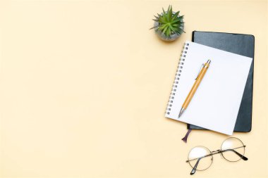 Siyah boş defter, kalem, gözlük, bej arka planda üst görüş. Üst düzey masa düzenlemesi. Zaman yönetimi, planlama konsepti. Asgari biçim, kopyalama alanı ve şablon logo tasarımı ile modelle.