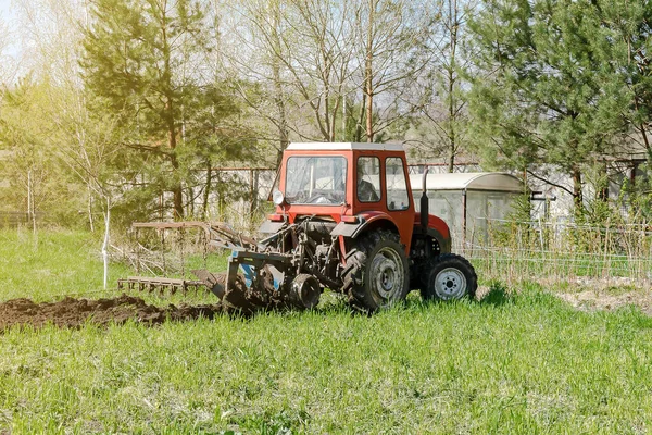 Modern vörös traktor gépek szántás mezőgazdasági területen rét a gazdaságban tavasszal ősszel. Mezőgazdasági termelő műveli és műveli a talajt vetés előtt növények és növények, természet vidéki színtér — Stock Fotó