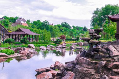 Bahçede güzel yeşil botanik manzara tasarımı, ağaçlar, çalılar, ahşap çardak, dekoratif göl havuzu, taze çimenlik alan. Sahne yaz bahçıvanlığı arka plan, konsept.