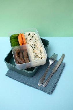 Depoda üç kompartıman pirinçli, sosisli ve yeşil arka planda sebzeli yiyecek hazırlıyorum. Sağlıklı dengeli beslenme, beslenme çantası paket paket paket hazır..