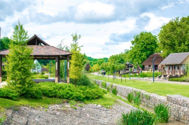 Bahçede güzel yeşil botanik manzara tasarımı, ağaçlarla, çalılarla ve banklarla dolu şehir parkı, ahşap çardak, taze çimenler. Sahne yaz bahçıvanlığı arka plan, konsept.