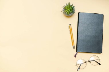 Siyah boş defter, kalem, gözlük, bej arka planda üst görüş. Üst düzey masa düzenlemesi. Zaman yönetimi, planlama konsepti. Asgari biçim, kopyalama alanı ve şablon logo tasarımı ile modelle.