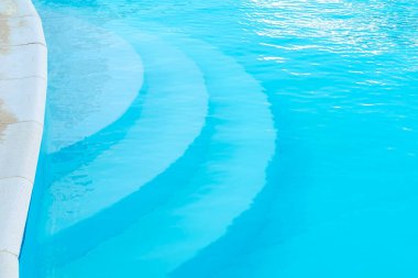 Mavi berrak suyla yüzme havuzu, küçük dalgalı dalgalar, sıcak güneşli bir günde otel otelinde. Yaz tropikal tatil konsepti.