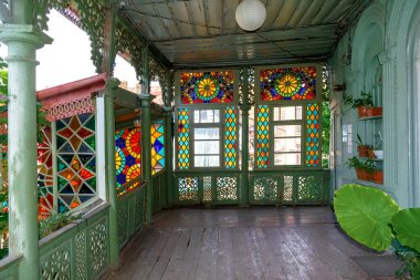 Ahşap balkon, açık teras ve eski tarihi kasaba bölgesinde renkli mozaik pencereli bir bina. Gürcistan 'ın ünlü ulusal geleneksel evi Tiflis, Gürcistan, 13 Haziran 2019.