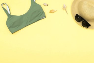 Seyahat tatili yatakları, aksesuar eşyaları, şapka, güneş gözlükleri, kıyafetler, mayo, sarı arka planda fotokopi alanı olan deniz kabukları, planlama macerası.
