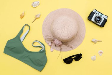 Seyahat tatili düz yatak, aksesuar nesneler, şapka, güneş gözlüğü, kıyafet, mayo, kamera, sarı arka planda deniz kabuğu, planlama yolculuğu macera, yolculuk.