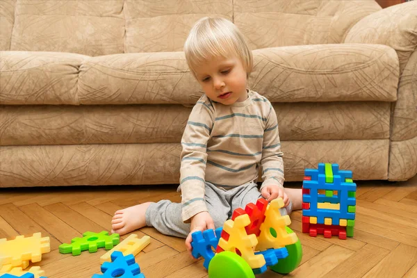 家で多色のコンストラクターと遊んでかわいいかわいいかわいい白人の男の子 赤ん坊の手はプラスチックブロックの塔を構築します 子供の論理開発と幼稚園のコンセプト — ストック写真