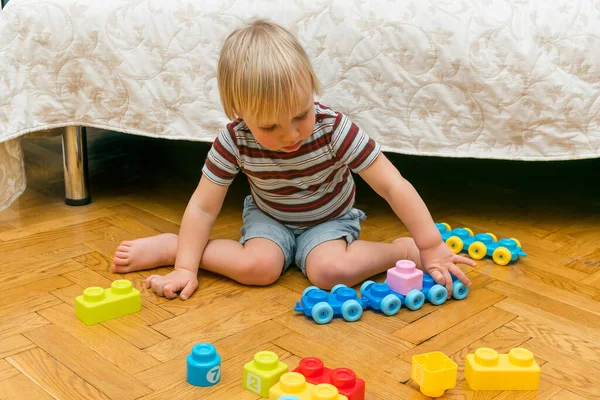 家で多色のコンストラクターと遊んでかわいいかわいいかわいい白人の男の子 赤ん坊の手はプラスチックブロックの塔を構築します 子供の論理開発と幼稚園のコンセプト — ストック写真