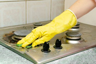 Kirli gaz sobasını yağdan temizlemek, yemek artıkları. Kadın eli koruyucu eldivende sünger bezi ve deterjan ile mutfak sobası yıkıyor. ev temizliği hizmeti kavramı.