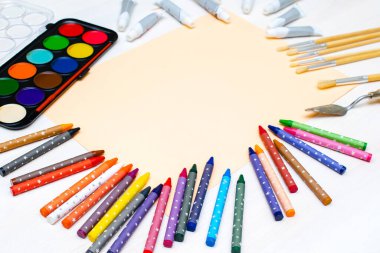 Suluboya boyaları, boya fırçaları, renkli kalemler, pastel boya kalemleri, boş suluboya kağıt pedler. Yaratıcılık yaratma süreci. Sanatçının eserleri beyaz masada. Resim malzemelerinin üst görünümü..