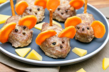 Küçük köfte faresi, havuç kulaklı köfte, tabakta peynir, çocuk partisi için yaratıcı ve eğlenceli yiyecek fikri. Ürkütücü Cadılar Bayramı tatlı ikramları için menü, yenilebilir şirin fare seçici odak.