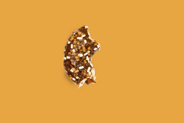 Creative concept of biting eating delicious sweet sugar brown black doughnut donut with glaze on brown background. Top view flat lay unhealthy dessert, Food concept, mock up, copy space.