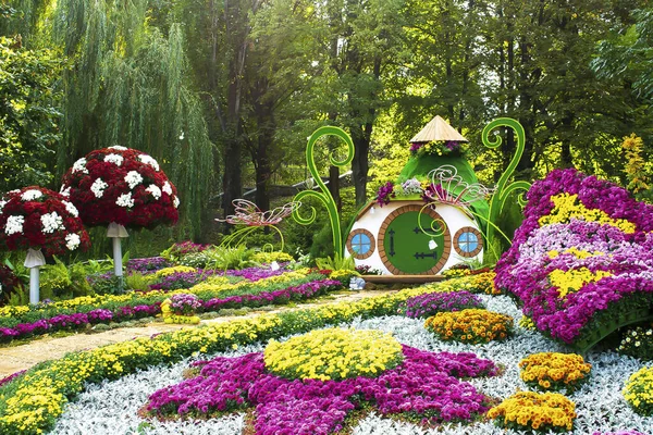 Famous flower exhibition in Kiev on Singing Field,Ukraine. Natural landscape design with flower beds, fairy tail house,trimmed bushes in city park at spring. home green garden in courtyard.
