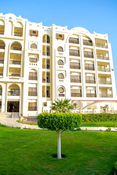 Lüks lüks, modern apartman tipi otel cephesi, sıcak güneşli bir günde yeşil çimenli tropikal tatil köyü. Yaz tropikleri Mısır 'da tatil, kaçış konsepti.