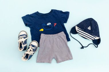 Yaz bebekleri mavi elbiseler ve panama şapkalı aksesuarlar, tişört, şort, spor ayakkabı. Modern moda çocuk kıyafeti. Bahar ya da yaz için çocuk kıyafetleri. Düz yatış, üst görünüm, genel görünüş, model.