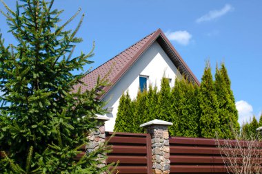 Arka bahçesi yüksek çitlerin arkasında özel bir banliyö evi. Yeşil thuja çitli ekolojik alanda güzel bir kır evi kompleksi. Modern mimari, zenginlik ve lüks konsept.