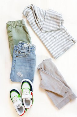 Spor ayakkabılı kazak ve kot pantolon. Beyaz arka planda bahar, sonbahar ya da yaz için bebek kıyafetleri ve aksesuarlar. Moda çocuk kıyafeti. Düz yatıyordu, üstten, yukarıdan..