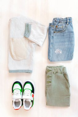 Spor ayakkabılı kazak ve kot pantolon. Beyaz arka planda bahar, sonbahar ya da yaz için bebek kıyafetleri ve aksesuarlar. Moda çocuk kıyafeti. Düz yatıyordu, üstten, yukarıdan..