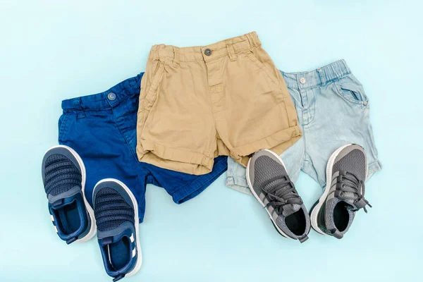 Summer babies blue clothes and accessories with jeans shorts,sneakers. Modern fashion kids outfit.Set of childrens clothing for spring or summer. Flat lay, top view,overhead,mockup