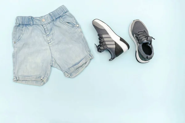 Summer babies blue clothes and accessories with jeans shorts,sneakers. Modern fashion kids outfit.Set of childrens clothing for spring or summer. Flat lay, top view,overhead,mockup with copy space —  Fotos de Stock