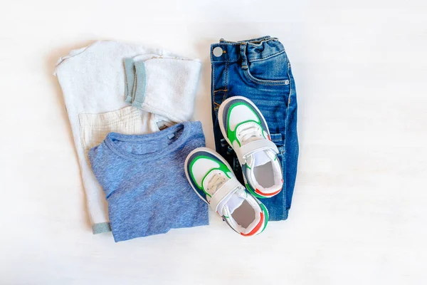 Jumper,t shirt and jeans pants with sneakers. Set of baby childrens clothes and accessories for spring, autumn or summer on white background. Fashion kids outfit. Flat lay, top view,overhead,mock up — Stock fotografie