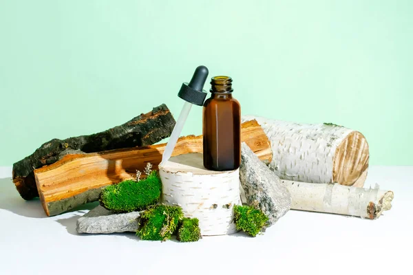 Cam damlatan kahverengi şişe kozmetik yağı, krem, gerekli ağaç kökü podyumunda serum, ağaç kabuğu ağacı, yeşil yosun. Doğal organik eko kaplıca, ilaç kavramı. Bitkisel homeopatik ürünler..