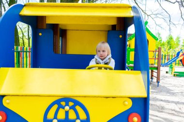 Oyuncak arabada, otobüste, çocuk parkında, trende oturan sevimli, komik, sarışın, küçük çocuk. Çocuklar fiziksel, duygusal gelişim ve çocuk yuvası, anaokulu konsepti.