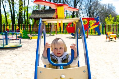 Sevimli, komik, sarışın, küçük çocuk çocuk. Oyuncak helikopterle çocuk parkında oturuyor ve biniyor. Çocuklar fiziksel, duygusal gelişim ve çocukluk kreşi, anaokulu konsepti..
