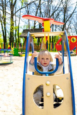 Sevimli, komik, sarışın, küçük çocuk çocuk. Oyuncak helikopterle çocuk parkında oturuyor ve biniyor. Çocuklar fiziksel, duygusal gelişim ve çocukluk kreşi, anaokulu konsepti..