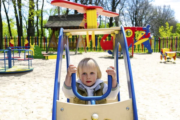Sevimli, komik, sarışın, küçük çocuk çocuk. Oyuncak helikopterle çocuk parkında oturuyor ve biniyor. Çocuklar fiziksel, duygusal gelişim ve çocukluk kreşi, anaokulu konsepti..