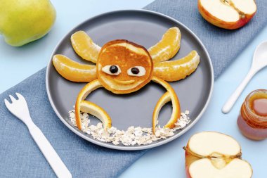 Krep, portakal, elma, tabakta bal gibi komik yengeç suratlı atıştırmalıklar. Sevimli çocuklar bebeğin tatlı tatlısını, sağlıklı kahvaltısını, öğle yemeğini, mavi arka planda yemek sanatını,.