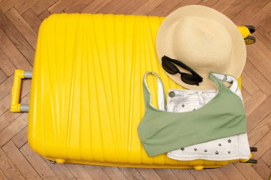 Seyahat yeri, seyahat aksesuarları, yaz şapkası, güneş gözlükleri, kıyafetler, fotokopi alanı olan sarı bavulda mayo, tatil tatili planları..