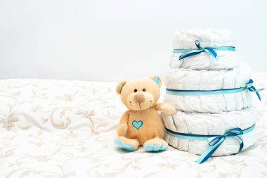 baby diaper cake present with toy teddy bear for the expectant family. set with blue colors for boy for baby shower with copy space.