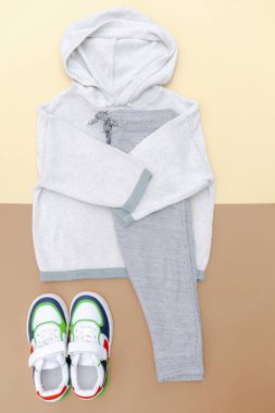 Spor ayakkabılı kazak ve kot pantolon. Bahar, sonbahar ya da yaz için bej rengi kahverengi arka planda bebek kıyafetleri ve aksesuarlar. Moda çocuk kıyafeti. Düz yatıyordu, üstten, yukarıdan..