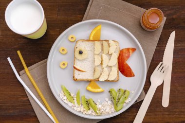 Muzlu, elmalı, portakallı, sütlü, ballı sandviç ekmeği. Çocukların tatlıları sağlıklı kahvaltı tabakları, ahşap arka plan, üst manzara..