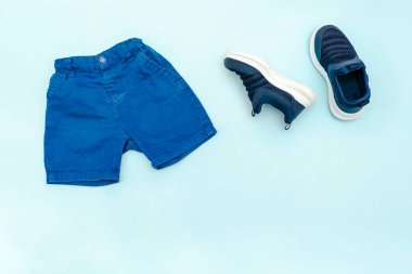 Summer babies blue sport clothes and accessories with jeans shorts,sneakers. Modern fashion kids outfit.Set of children's clothing for spring or summer. Flat lay, top view,overhead,mockup.