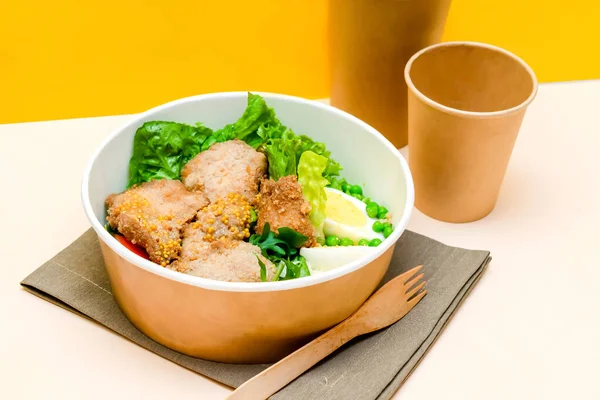 Healthy food lunch in kraft paper carton eco friendly box disposable bowl packaging container, cup on yellow background. chicken, eggs, greens. Take away delivery. environment protection top view.