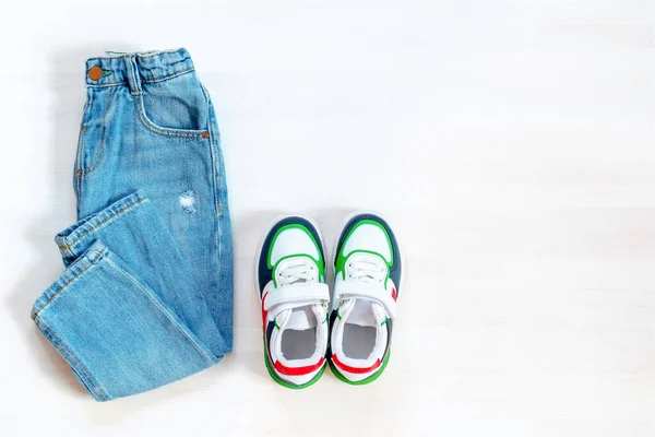 jeans pants with sneakers. Set of baby children\'s clothes and accessories for spring, autumn or summer on white background. Fashion kids outfit. Flat lay, top view, overhead.