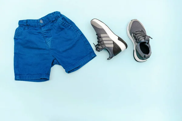 Summer babies blue clothes and accessories with jeans shorts,sneakers. Modern fashion kids outfit.Set of children's clothing for spring or summer. Flat lay, top view,overhead,mockup with copy space.