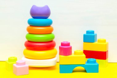 Renkli piramit, inşaatçı, çocuklar için oyuncak blokları beyaz sarı arka planda oynuyor, bebeğin çocukluk gelişimi, küçük çocuğun konsepti için eğitici mantık oyuncakları.
