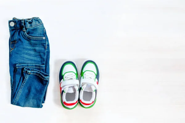 Jeans pants with sneakers. Set of baby children\'s clothes and accessories for spring, autumn or summer on white background. Fashion kids outfit. Flat lay, top view, overhead,copy space.