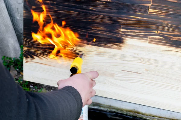Erkek eller ahşap masayı yakıyor, masa, ocaklı yüzey, dışarıda odun yakan el işi. Balonla gaz ocağını tutan ve arka bahçede ateş yakan adamı kapatın..