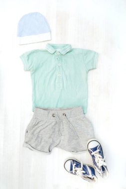 Şirin bir bebek tulumu, şort, şapka, spor ayakkabı. Çocuklar, çocuk kıyafetleri, elbiseler ve pastel mavisi aksesuarlar. Yenidoğan, çocuk modası, erkek kıyafeti. Düz yatış, üst görünüm, model.