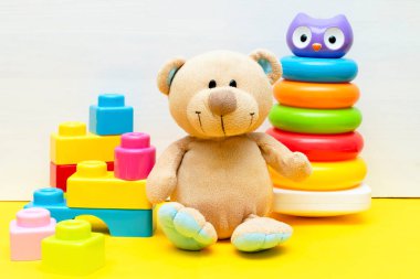 Renkli piramit, inşaatçı, çocuklar için oyuncak blokları beyaz sarı arka planda oynayan oyuncak ayı, bebeğin çocukluk gelişimi, küçük çocuğun konsepti için eğitici mantık oyuncakları,