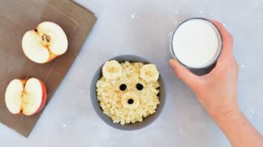 Video animation Funny kids childrens baby's healthy breakfast lunch porridge in bowl look like bear face with banana,kiwi, dried berry fruits,milk,honey,hand puts milk glass on table.dessert food art.